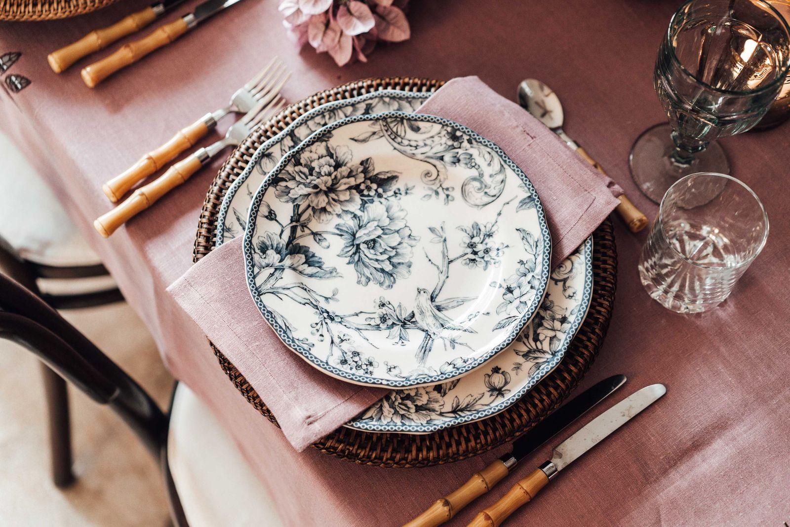 Patterned plates and cutlery on rose linen